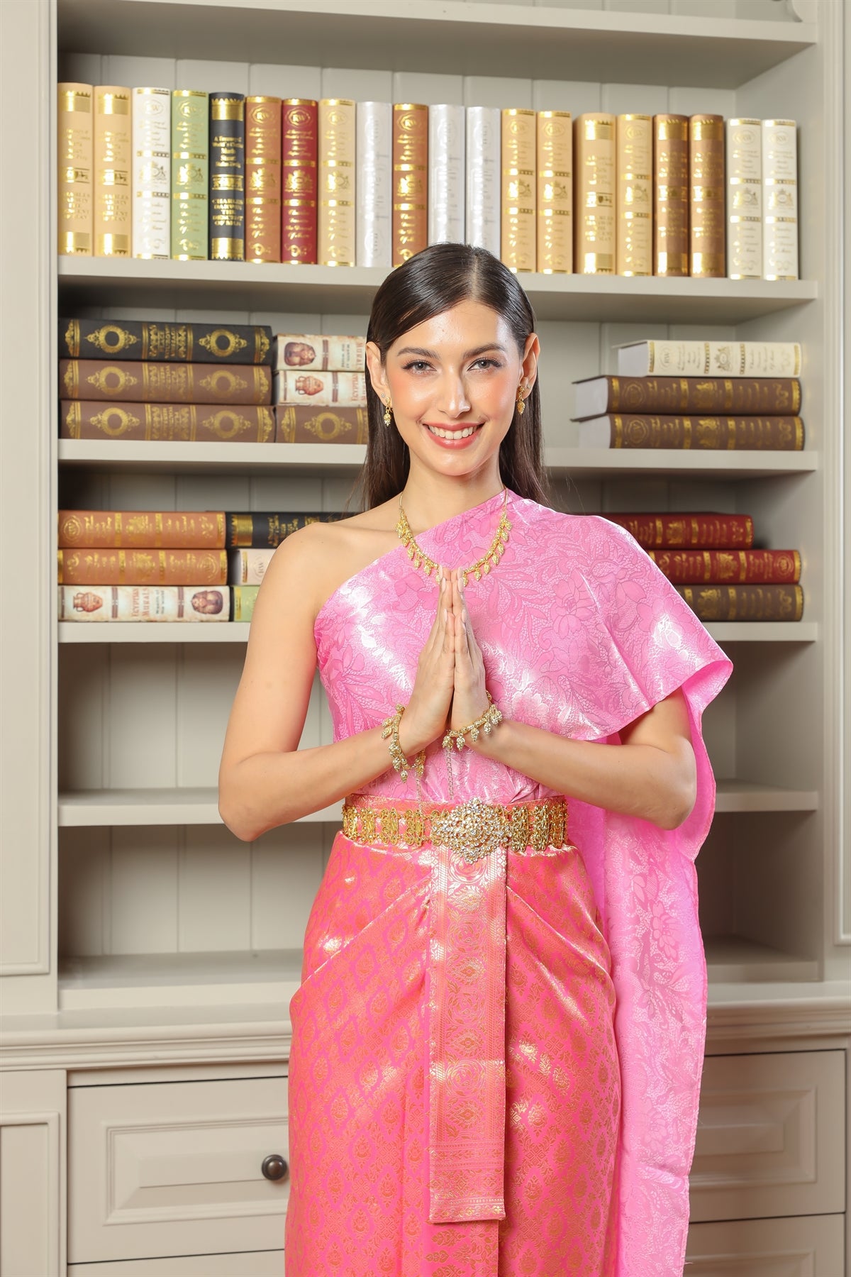 A woman happily greets guests in her traditional Thai dress.
